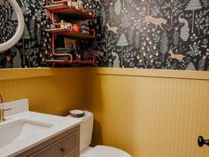 a bathroom with a toilet, sink and shelving unit in the wall behind it