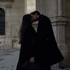 a man and woman kissing in front of a building