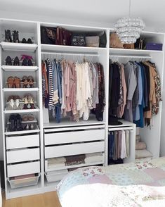 a white closet filled with lots of different types of clothes and shoes on top of drawers