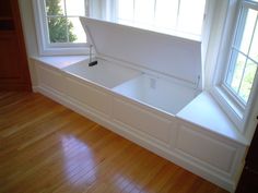 an empty bench in front of a window on a hard wood floored room with hardwood floors