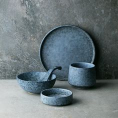 two bowls and one plate are sitting on the floor next to each other, in front of a stone wall