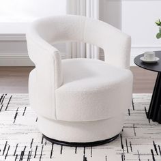 a white chair sitting on top of a rug next to a black and white table