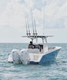 a man sitting on the back of a white boat in the middle of the ocean