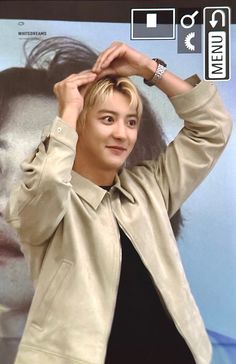 a young man is posing in front of a poster