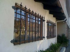 a building with many windows and bars on the side of it's wall next to a sidewalk