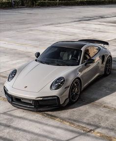 a silver porsche sports car parked in an empty parking lot with no one around it