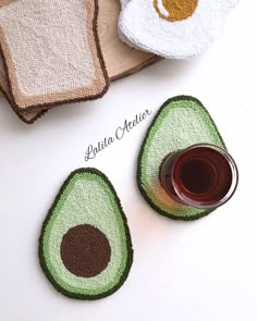 an avocado shaped coaster next to a glass of wine and some towels on a table