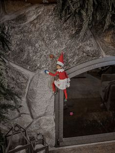 an elf doll sitting on top of a stone wall