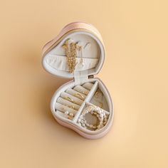 an open white box with jewelry inside on a beige background, the lid is closed and there are two pairs of scissors in it