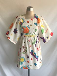 "One-of-a-kind, handmade novelty cotton mini dress made from a 1970's Butterick pattern! Dress features kimono sleeves, square neck, A line silhouette in a vintage Hawaiian print with kids drawings and writing. A hand crocheted piece of yellow cotton lace decorates the front waist seam. Waistline is between an empire and a natural waist. Dress is lined in the bodice and zips up the back with a plastic teeth zipper.  Never worn, made specially for Kinfauns!  Fabric designed and printed in Hawaii Natural Waist Dress, Hawaiian Print Fabric, Kimono Sleeve Dress, Cotton Mini Dress, Dress Kimono, Blue Summer Dresses, Full Skirt Dress, Butterick Pattern, Kids Drawings