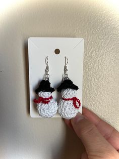 a pair of crocheted snowman earrings hanging from a hook