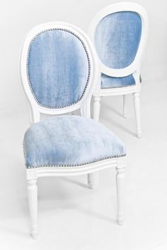 two white chairs with blue upholstered cushions