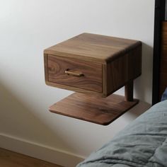 a wooden night stand sitting on top of a bed