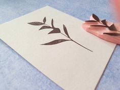 a rubber stamp with a plant on it next to a piece of paper that has been cut