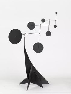 a black sculpture with circles and pendulums hanging from it's sides on a white background