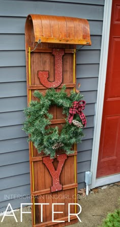 a wooden sign that says joy with wreaths on it and the letters joy are hanging from