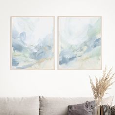 two paintings hang on the wall above a couch in a living room with a vase