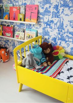 two stuffed animals sitting on top of a yellow bed in a child's room