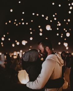 a man and woman kissing in front of many lit up lanterns flying above them at night