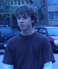 a young man standing in front of parked cars