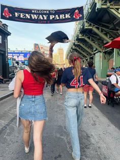 two girls walking down the street in front of fenway park