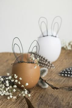 two eggs with hair pins in them sitting on a wooden table next to each other