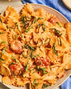 a white bowl filled with pasta covered in sauce and toppings on top of a blue towel