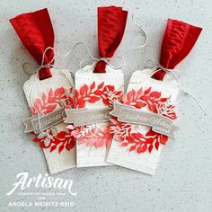 four tags with red flowers and ribbons on them