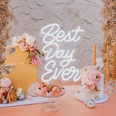 a table topped with two cakes covered in frosting next to candles and pink flowers