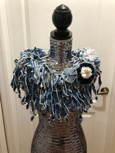 a mannequin with blue and white flowers on it's neck, sitting in front of a door