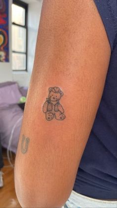 a man with a tattoo on his arm holding a teddy bear in front of him