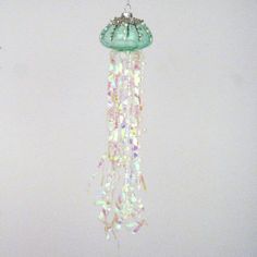 a green light hanging from the ceiling with beads and chains attached to it's sides