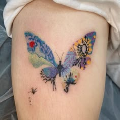 a woman's thigh with a colorful butterfly tattoo on her left side ribcage