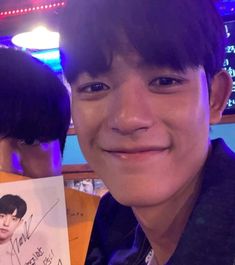 a young man holding up a photo with an autographed person on the front