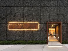 the front entrance to food and forest restaurant at night with illuminated sign on stone wall