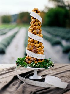 there is a tall cake made out of nuts on top of a wooden table in the middle of a field