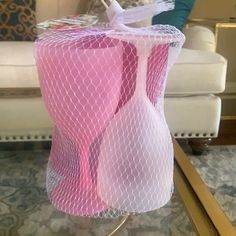 a pink mesh bag sitting on top of a metal stand next to a white couch