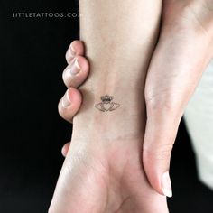 two hands holding each other with a small tattoo on the wrist