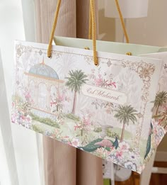 a paper bag hanging from the ceiling in front of a window with flowers and palm trees on it