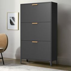 a gray cabinet with gold handles next to a chair