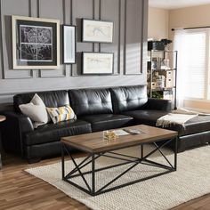 a living room with black leather couches and pictures on the wall above them,