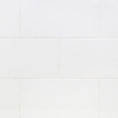 an orange and white cat laying on the floor next to a tiled wall in a bathroom