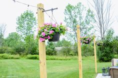 hanging planters filled with pink flowers on wooden poles