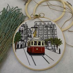 an embroidered ornament with a red trolley car on the tracks in front of buildings