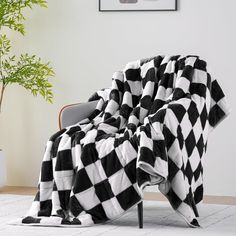 a black and white checkered blanket sitting on top of a chair next to a potted plant