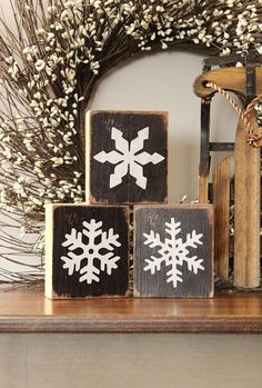 three wooden blocks with snowflakes on them sitting on a table next to a wreath