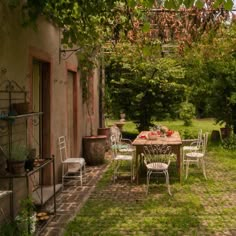 an outdoor table and chairs in the middle of a yard with potted plants on either side