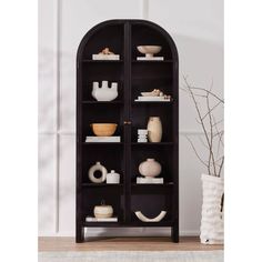 a black bookcase with white dishes and vases