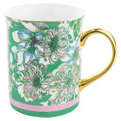 a green and pink coffee cup with gold trimmings on the rim, decorated with flowers