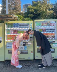 a man and woman kissing in front of a vending machine